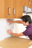 construct Sheets for the staying Places man installing the rest of the tile sheets while preparing to put in a glass mosaic backsplash