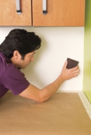 man planning the wall surface to install a glass mosaic backsplash